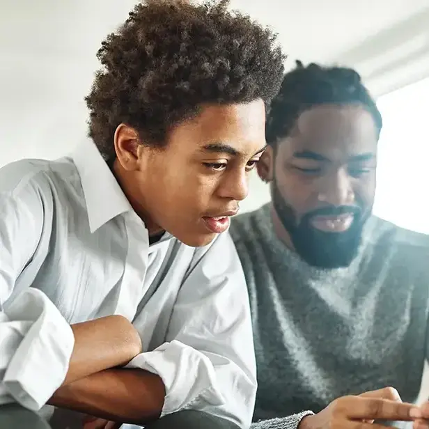 a man and boy looking at a cellphone