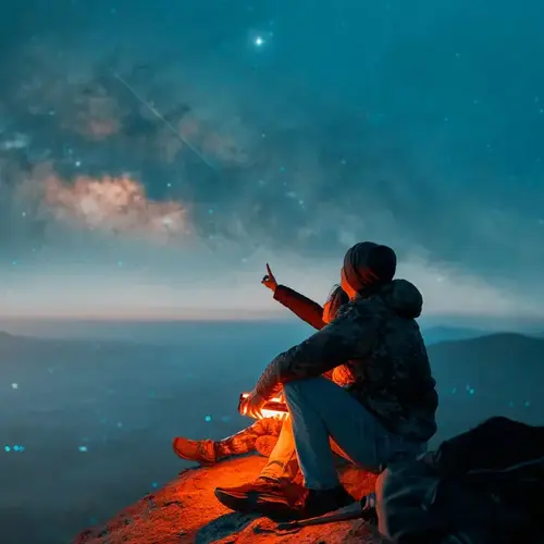 Silhouettes of a latin couple sitting on the top of the hill looking at shooting stars and the milky way in the background