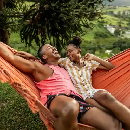 LGBTQIA+ friends lying on hammock on house yard
