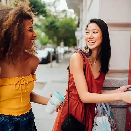 two women standing next to an ATM